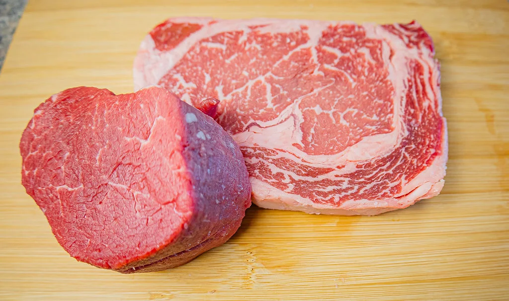 Fresh ribeye and filet cuts on a wooden board at Kenyon’s Meat Market