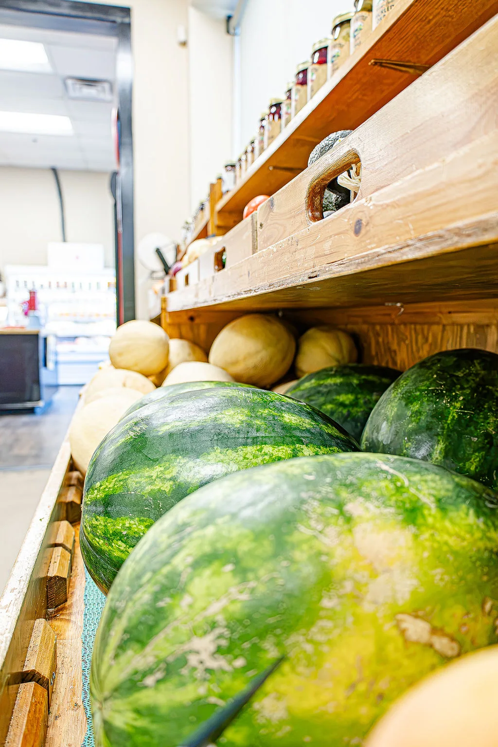 Watermelons and cantaloupes on wooden produce shelves